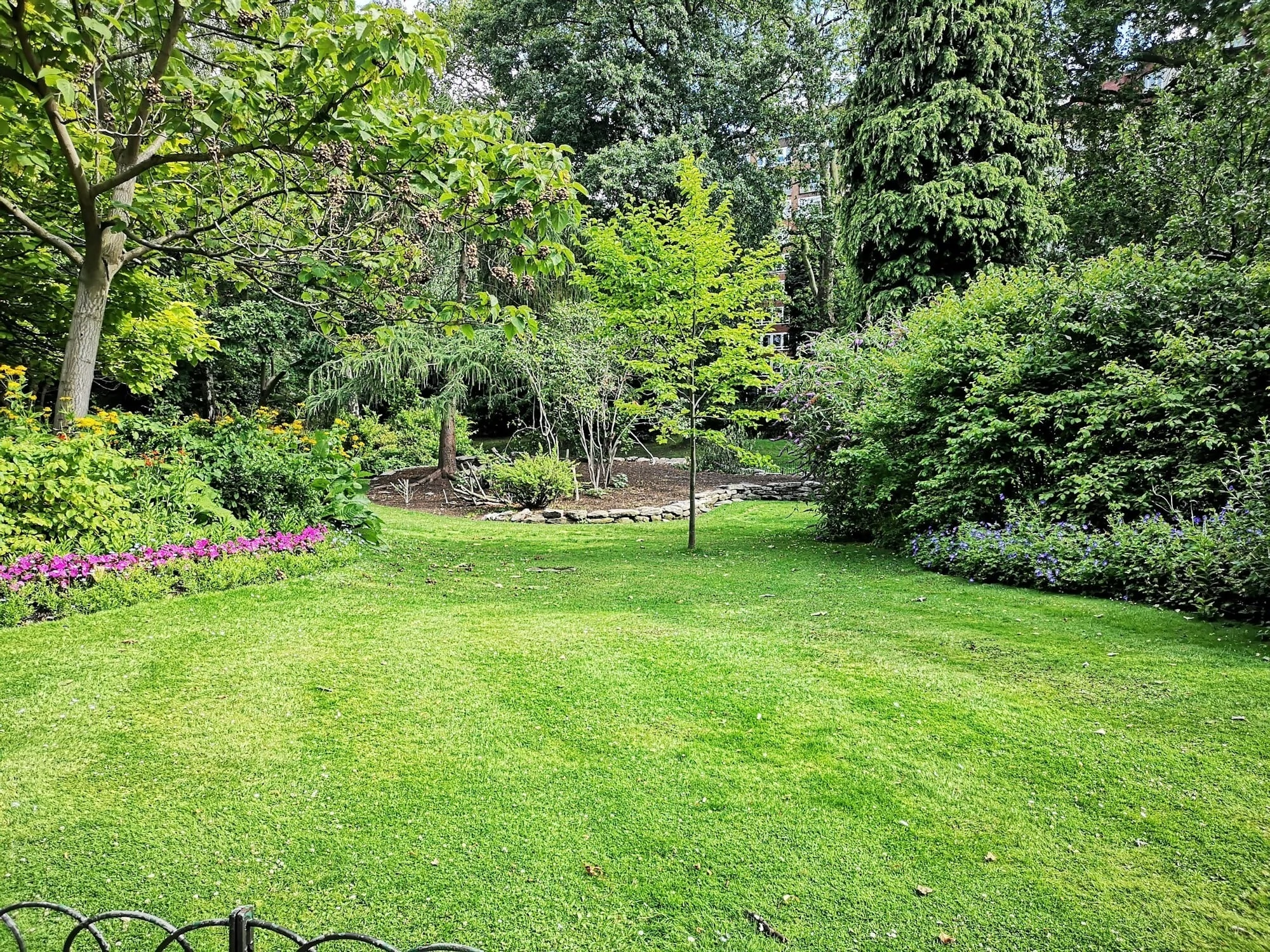 Big green garden, very well taken care of, big green trees.