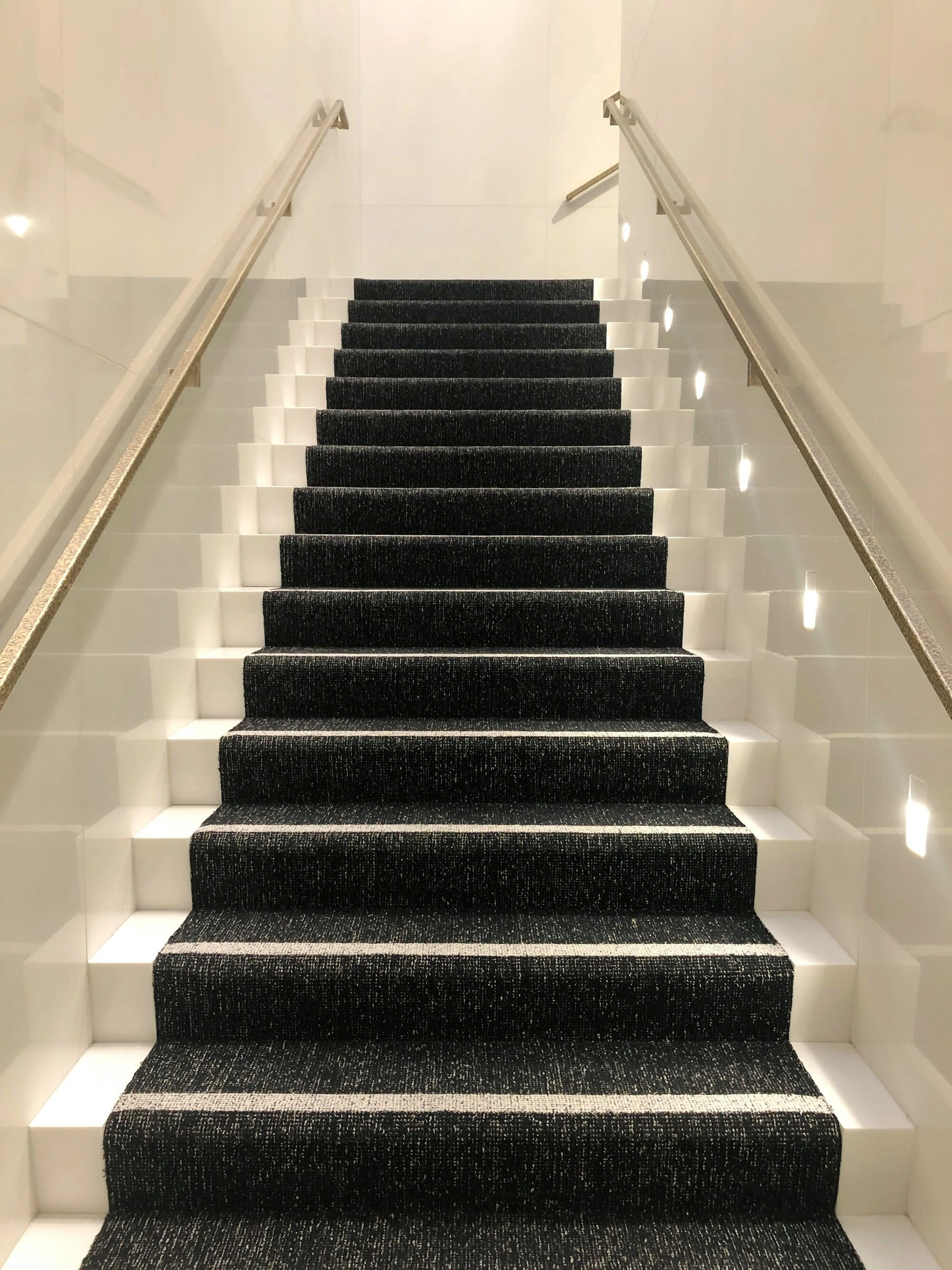 Luxury Modern staircase, white walls fancy black and white carpet with gold hand rails.