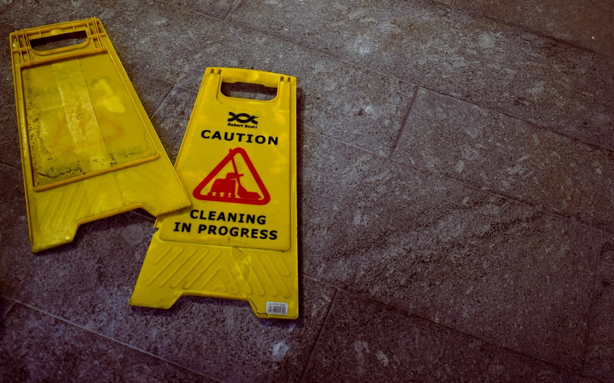 Caution cleaning in progress sign knocked over on concrete floor
